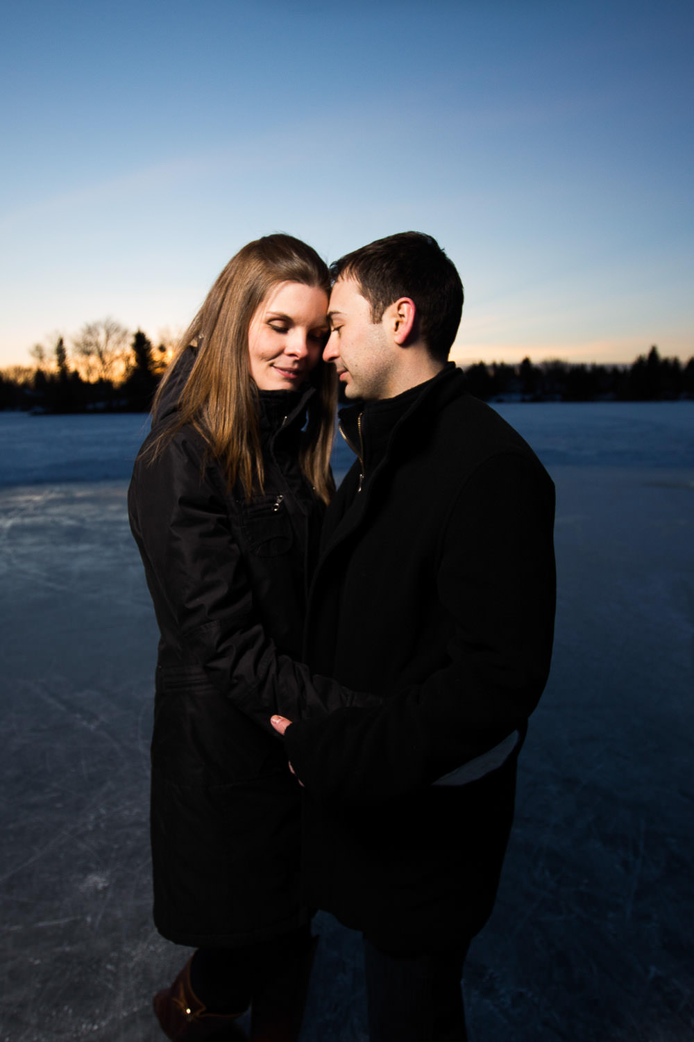 Winter engagement photography on frozen lake with hockey net